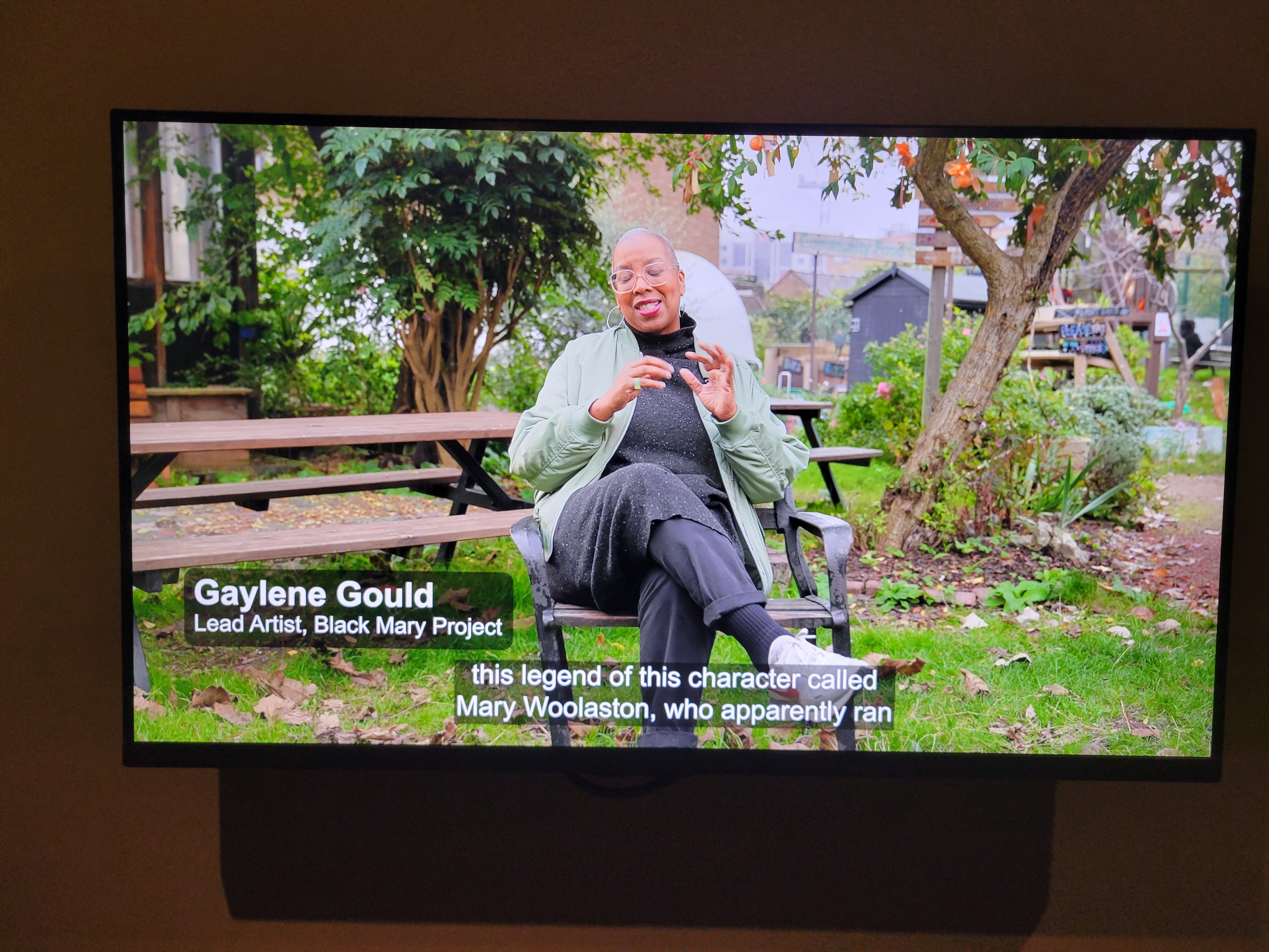 Artist Gaylene Gold sits on a bench at Calthorpe Community Garden