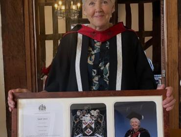 Sarah with her honorary degree wearing cap and gown