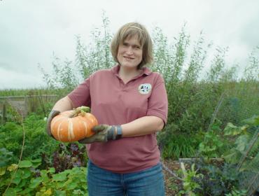 Woman standing in a garden holding a squash