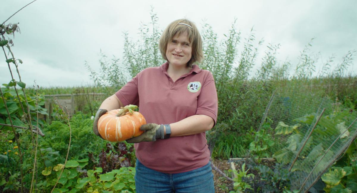Woman standing in a garden holding a squash