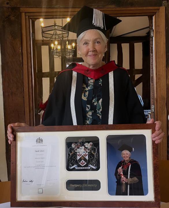 Sarah with her honorary degree wearing cap and gown