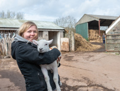 Woman holding a lamb on a care farm