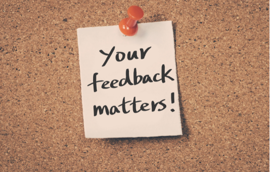 Note pinned to cork board reading 'Your feedback matters!'